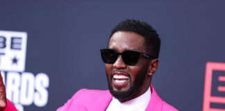 Man in pink suit and sunglasses smiling.