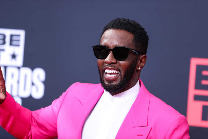 Man in pink suit and sunglasses smiling.