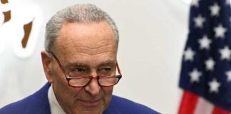 Man with glasses near American flag indoors