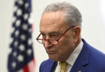 Man with glasses in front of American flag