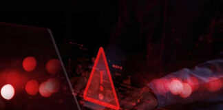 Red warning triangle on computer screen, hands typing.