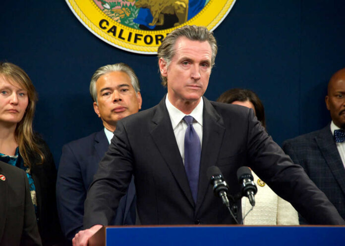 gavin-newsom638551334 Person speaks at podium with California seal behind.