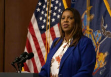 Woman speaking at a podium with flags behind her