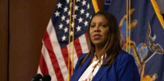 Woman speaking at a podium with flags behind her
