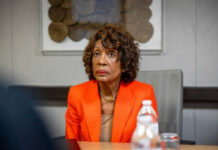 Woman in orange blazer seated at a table
