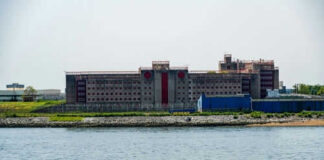 Large building by water with a stony shore
