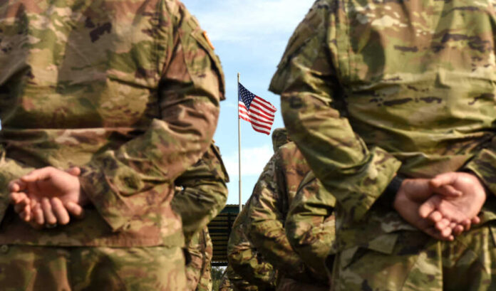 Soldiers standing in formation with an American flag in the background