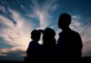 Silhouette of a family against a colorful sunset sky