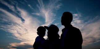 Silhouette of a family against a colorful sunset sky