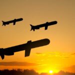 Silhouettes of missiles flying against a sunset backdrop