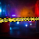 Police crime scene tape with emergency lights in the background