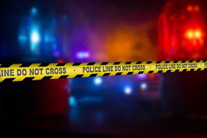 Police crime scene tape with emergency lights in the background