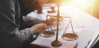 A set of legal scales on top of law books with a person working in the background