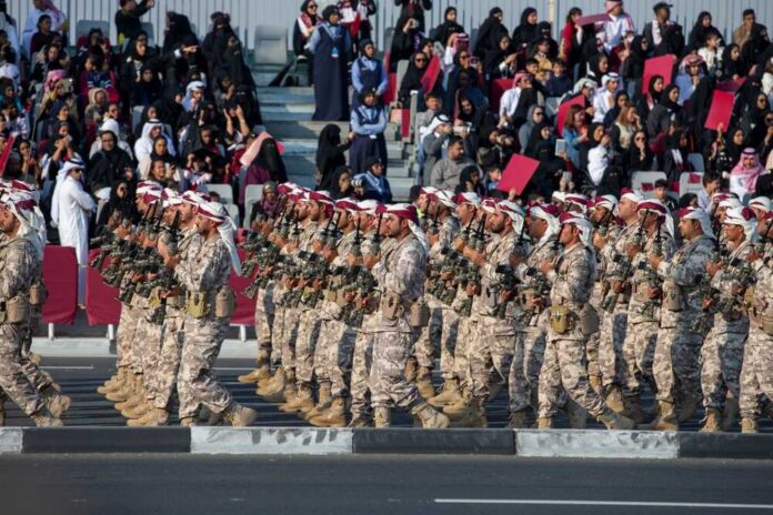 Soldiers in military uniforms marching in a parade with a crowd in the background