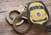 Handcuffs and a police badge on a wooden surface