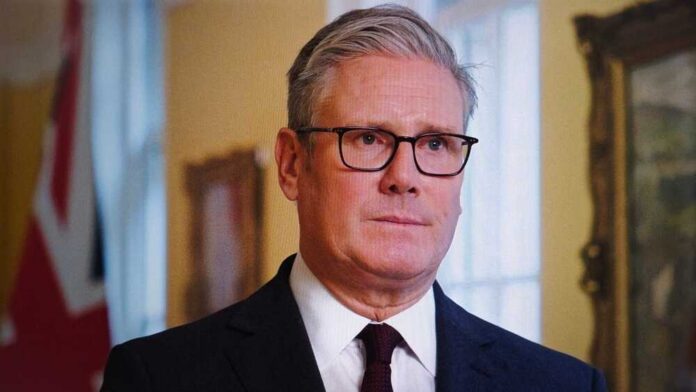 A man in formal attire with glasses, looking serious in an indoor setting