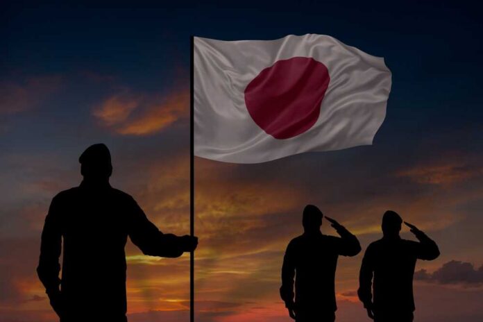 shutterstock_2717260557.jpg Silhouettes of soldiers saluting the Japanese flag against a sunset