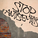 Stop antisemitism graffiti on a worn brick wall