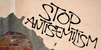 Stop antisemitism graffiti on a worn brick wall