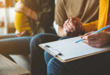 Pregnant woman couple and counselor with clipboard writing