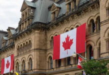 Historic building with large Canadian flags displayed outside