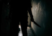 Silhouette of person holding knife in dark corridor
