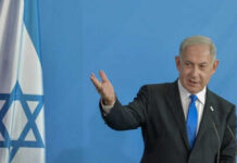 Man speaking next to Israeli flag.