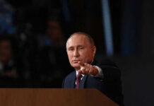 Person pointing while speaking at a podium