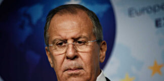A serious-looking man in formal attire at a press conference
