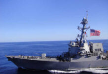 Navy’s Tense Standoff – Strait of Hormuz Heats Up A naval destroyer sailing in the ocean with an American flag