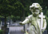 Weathered angel statue holding a cross in a cemetery