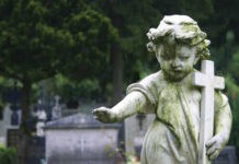 Weathered angel statue holding a cross in a cemetery