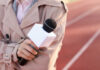 A reporter holding a microphone on a running track