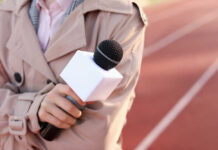 A reporter holding a microphone on a running track