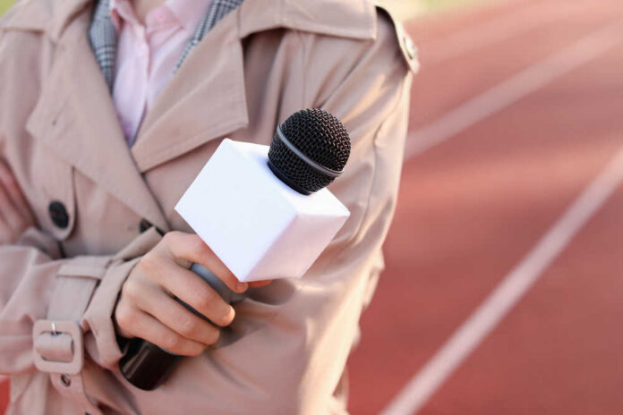 A reporter holding a microphone on a running track