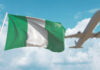 Nigerian flag waving with an airplane flying in the background