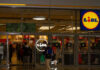 Entrance of a Lidl grocery store with customers shopping