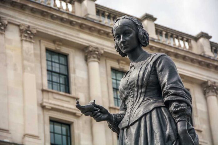 Bronze statue of a woman holding a bird in an urban environment