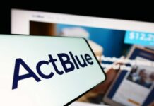 Close-up of a mobile device displaying the ActBlue logo with a blurred background of a fundraising website