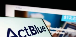 Close-up of a mobile device displaying the ActBlue logo with a blurred background of a fundraising website