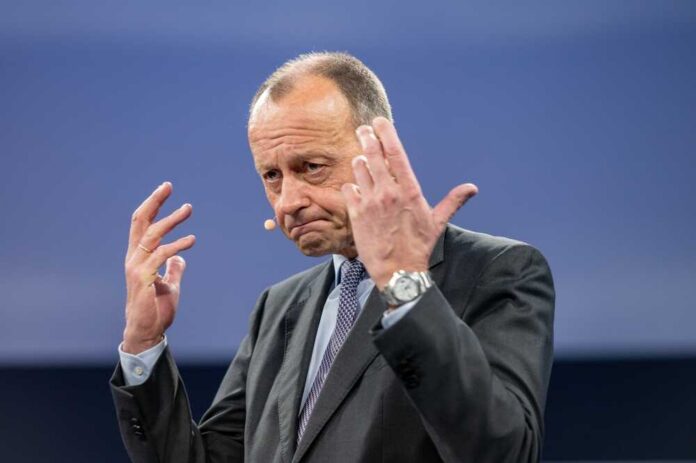 A man in a suit gesturing while speaking at a conference