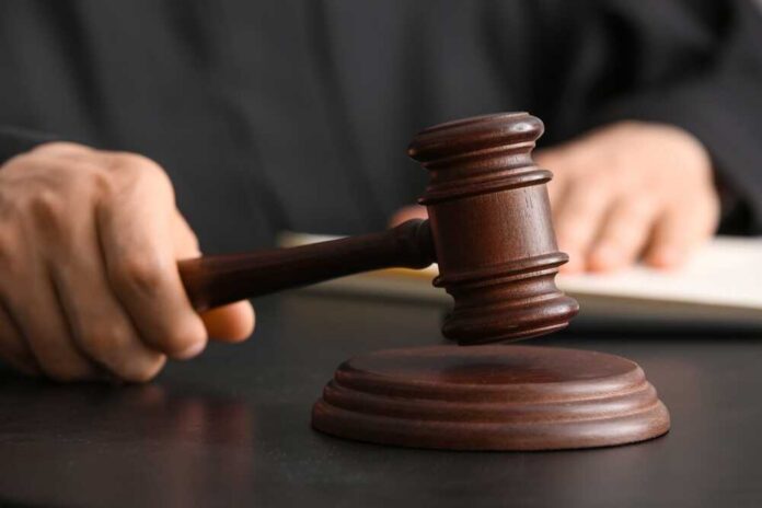 A judge's hand holding a gavel above a wooden block