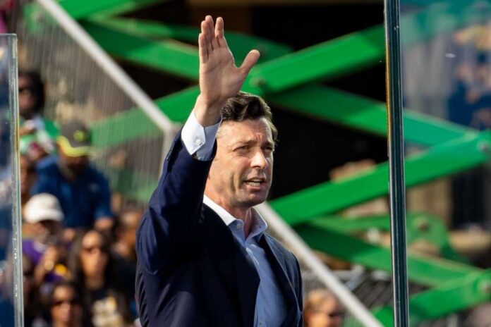 A man in a suit gesturing while speaking at an outdoor event