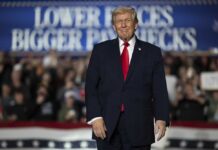 A speaker at a political rally smiling in front of a cheering crowd