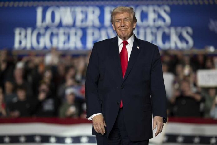 A speaker at a political rally smiling in front of a cheering crowd