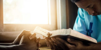 Two individuals engaged in prayer with a Bible