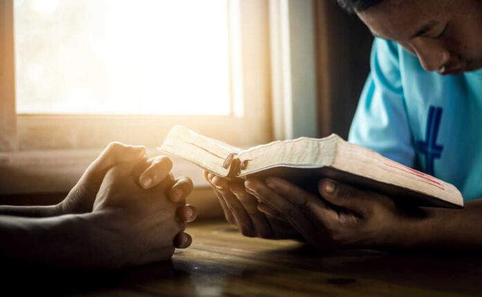 Two individuals engaged in prayer with a Bible