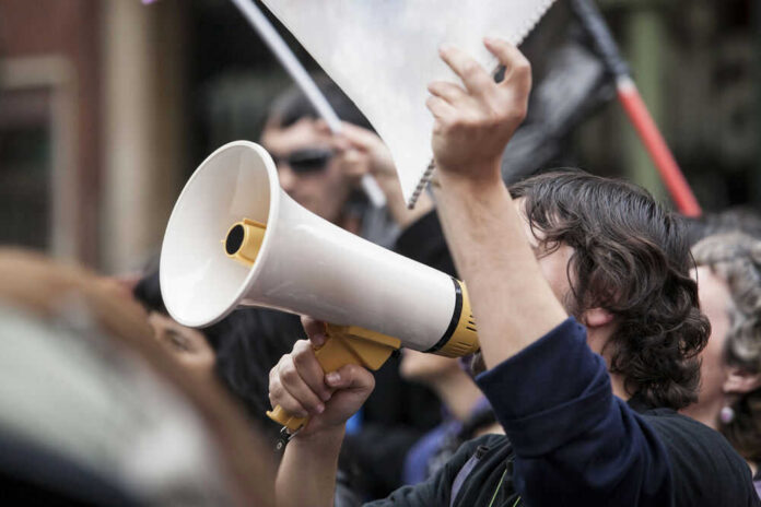 Person holding megaphone at a protest rally.