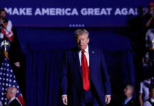 Person in red tie at rally under blue banner