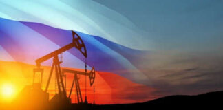 Oil pumps silhouetted against Russian flag and sunset.